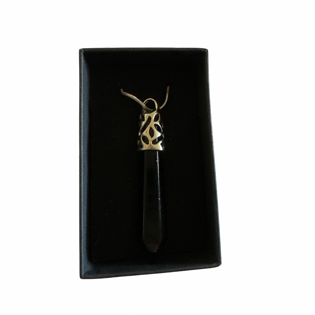 Black obsidian point pendant on a chain in a black jewelry box.