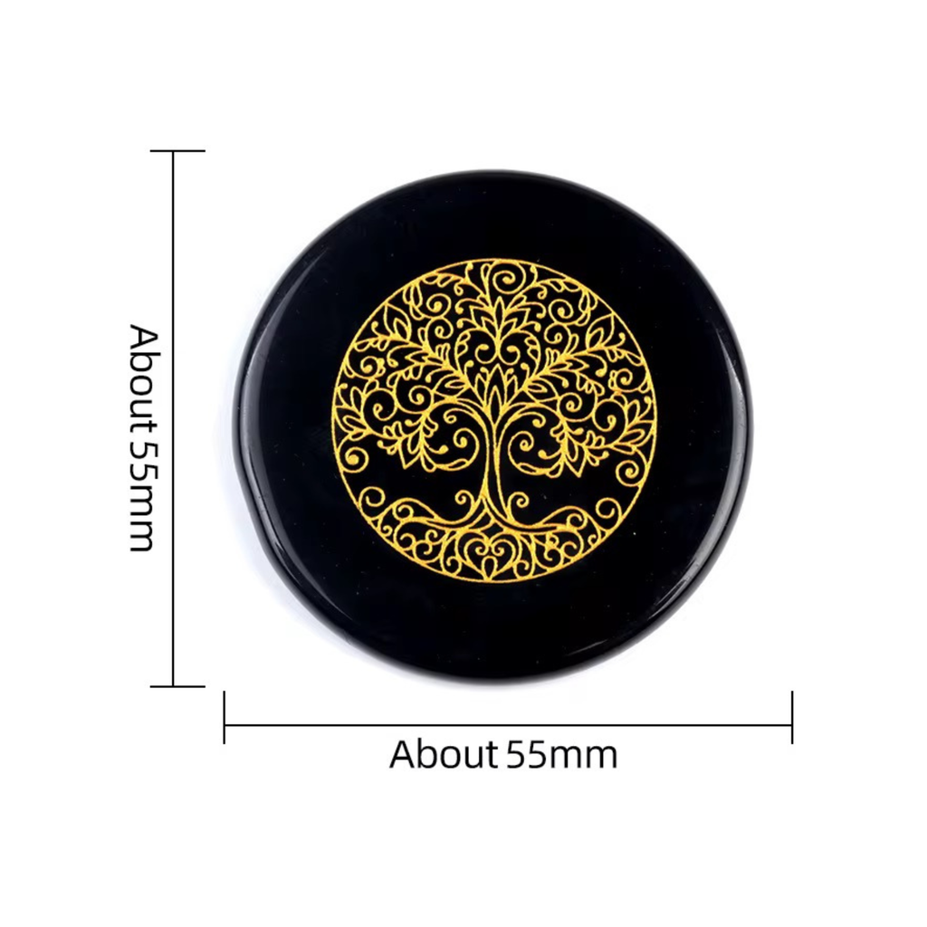 A round black stone carved with tree of life design in the center.