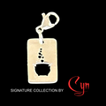 Silver stainless steel charm with lobster clasp on top. Rectangle tablet shape featuring cut out design of cauldron with bubbles floating up. Set on black background, branded designed by 'Cyn' 
