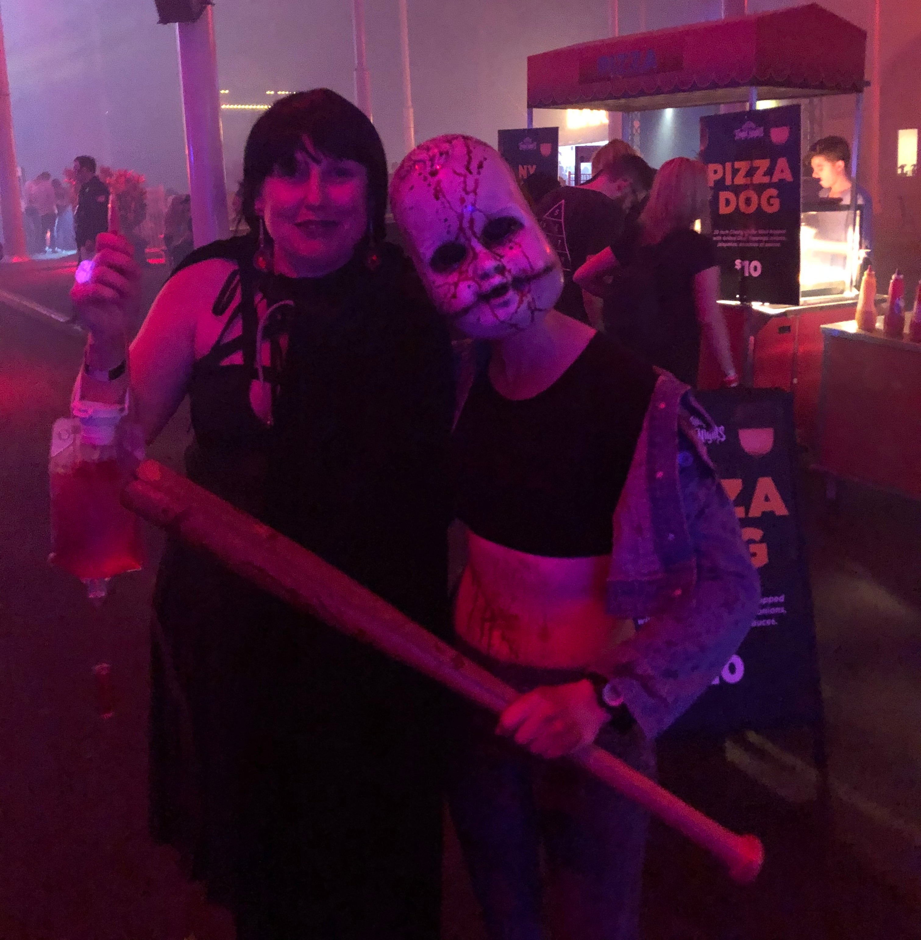 Cyn dressed in black with long black hair standing with a halloween character at fright night movie world for a photo