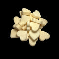 A pile of small, heart-shaped cream-colored wax melts arranged on a solid black background.