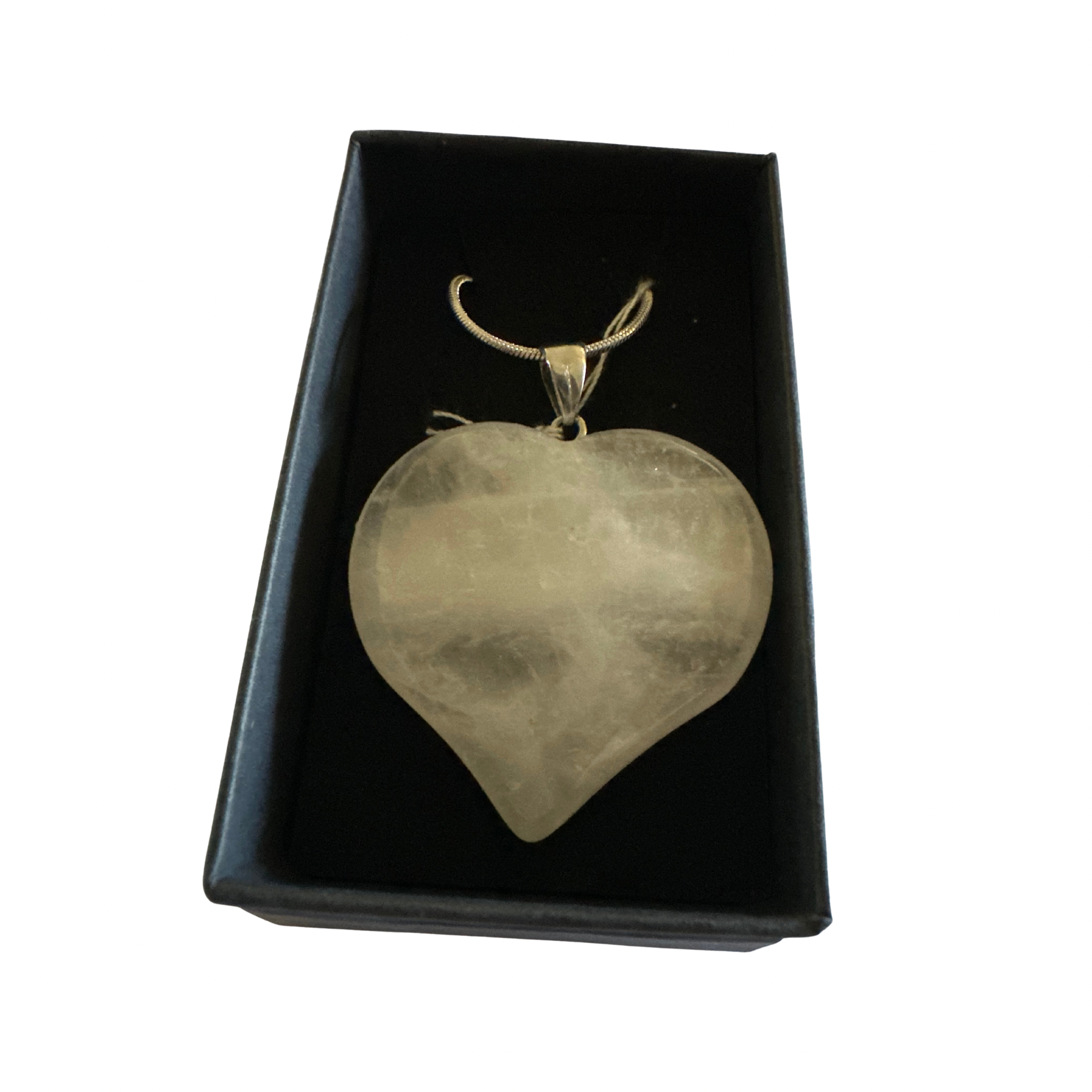 Clear quartz heart pendant on a silver chain inside a black jewelry box.