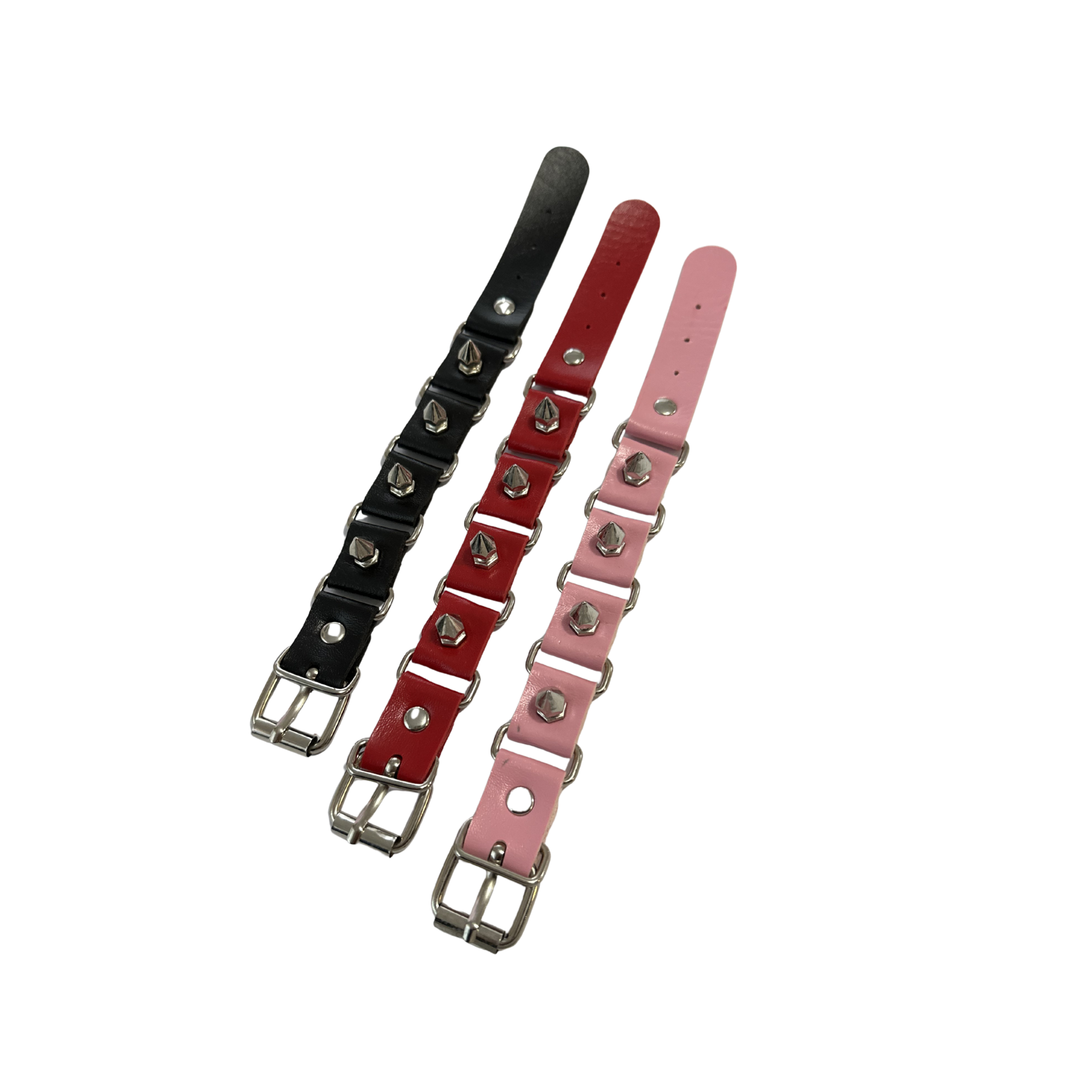 3 spike wrist cuffs laying flat next to each other, black, red and pink