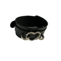 A black pu leather wrist cuff with a silver metal heart-shaped ring shown on a plain white background.